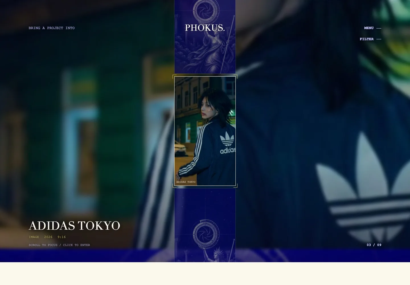The homepage reel with a campaign still held inside gold reticle brackets, a blurred plate of the same still filling the background, and a readout naming the project, kind, year and frame.